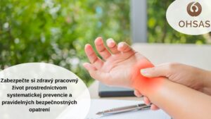Ruky osoby držia zápästie s vyznačenou pulzujúcou bolesťou, v pozadí na stole leží papier a pero.